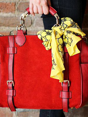 Tied casually as a bow to the handle. This look works with small and larger scarves as well as Twilly scarves.