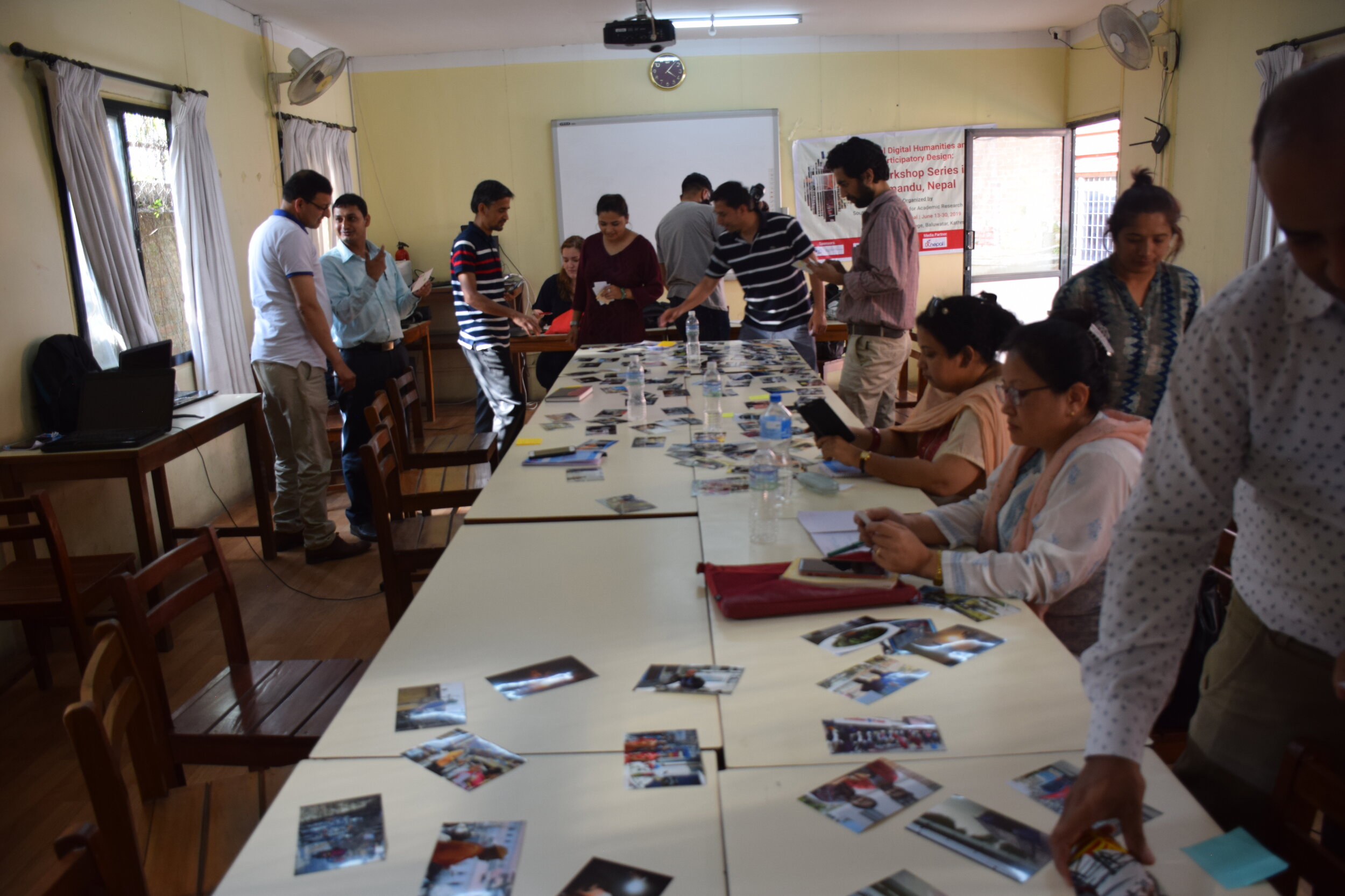 A group of students arranges pictures around a long table in a classroom.