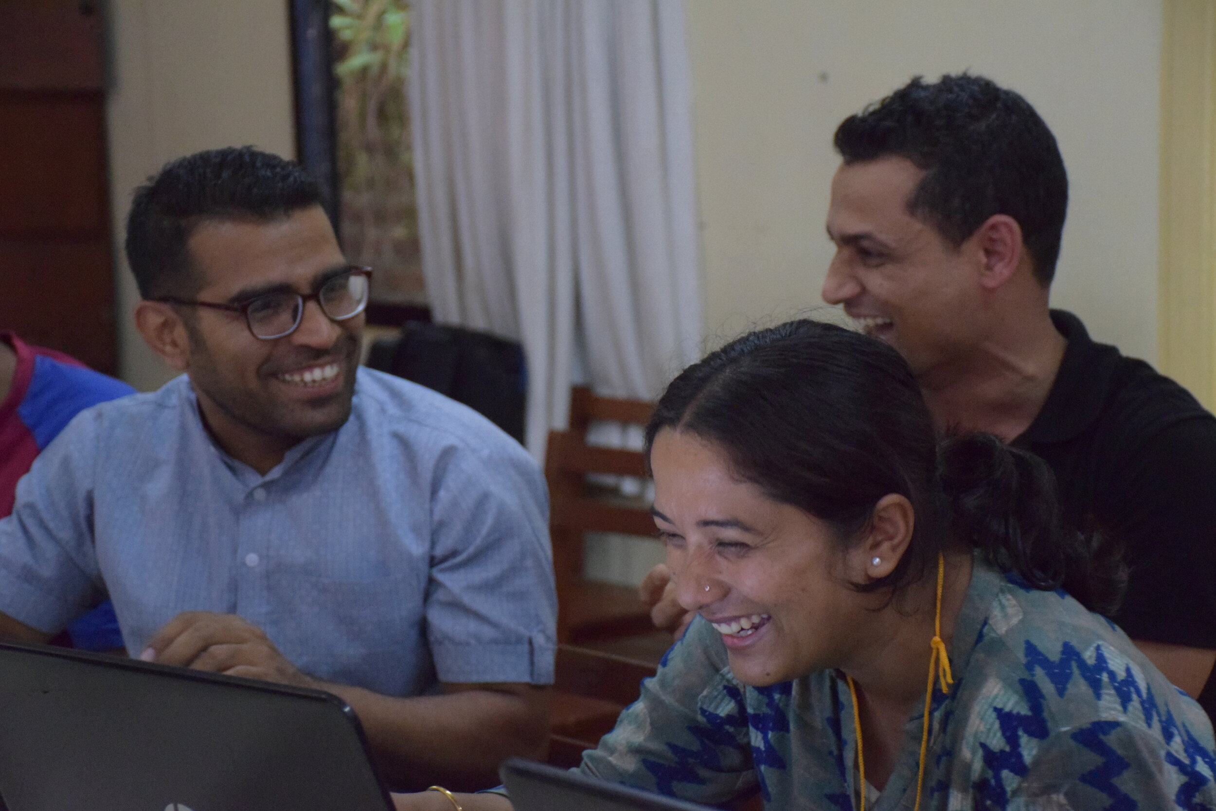 Three students laugh as they work together on a computer.