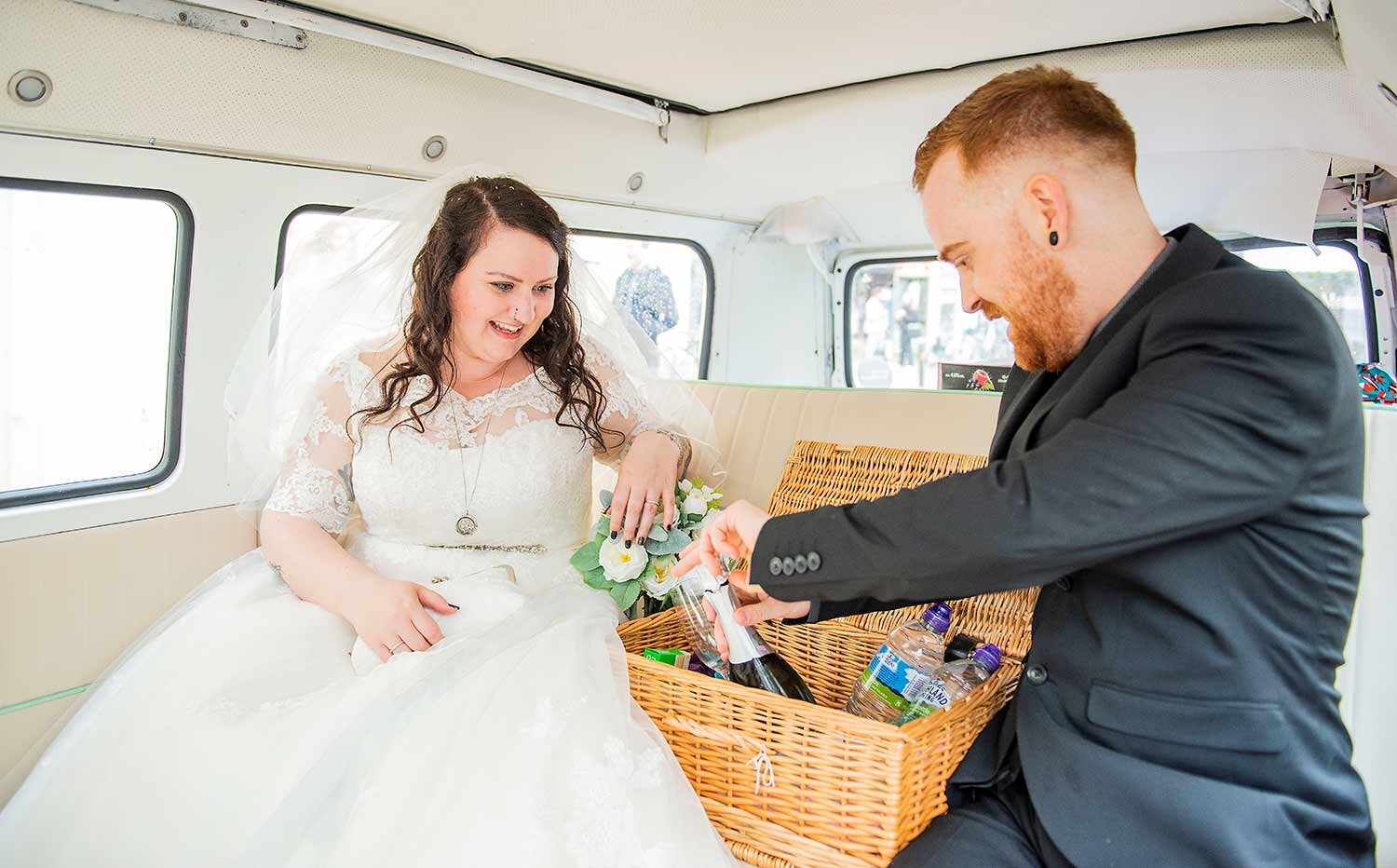 Bride and groom celebrating drinks in wedding van