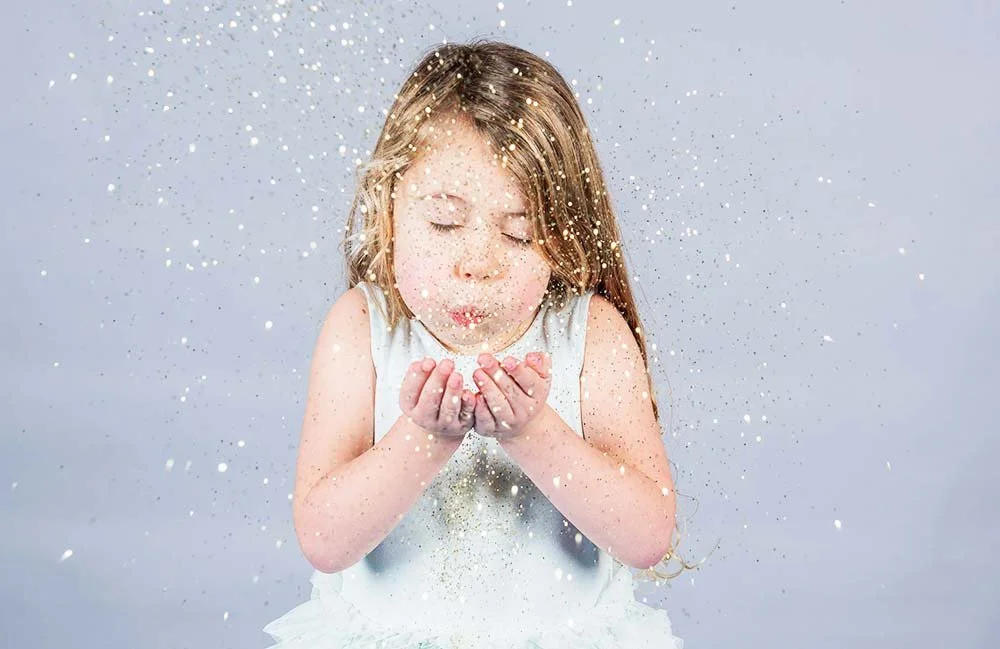 Young girl blowing glitter during photoshoot in Littlehampton studio.