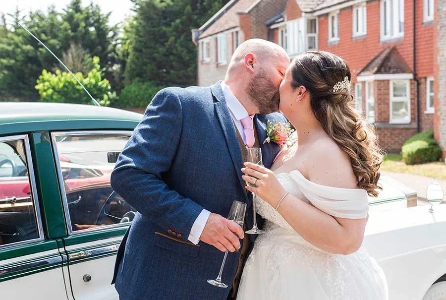 Sussex couple kissing with glass of champagne in their hands
