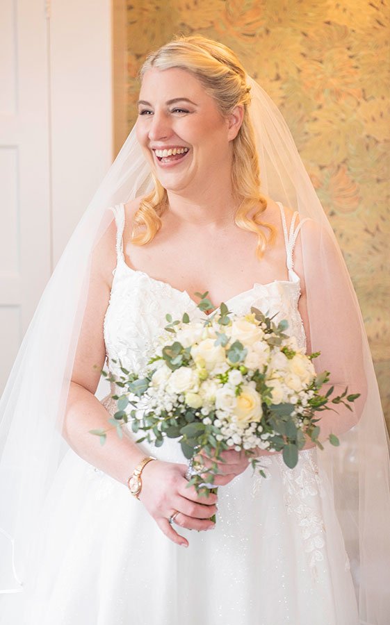 Bride laughing in her wedding dress during bridal prep, captured in a natural candid moment.