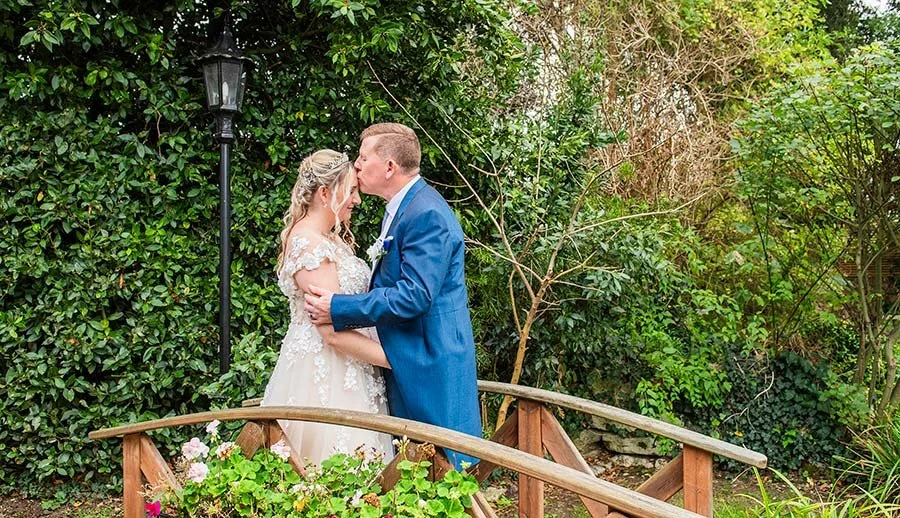 Groom kissing the bride's forehead at Angmering Manor Hotel.