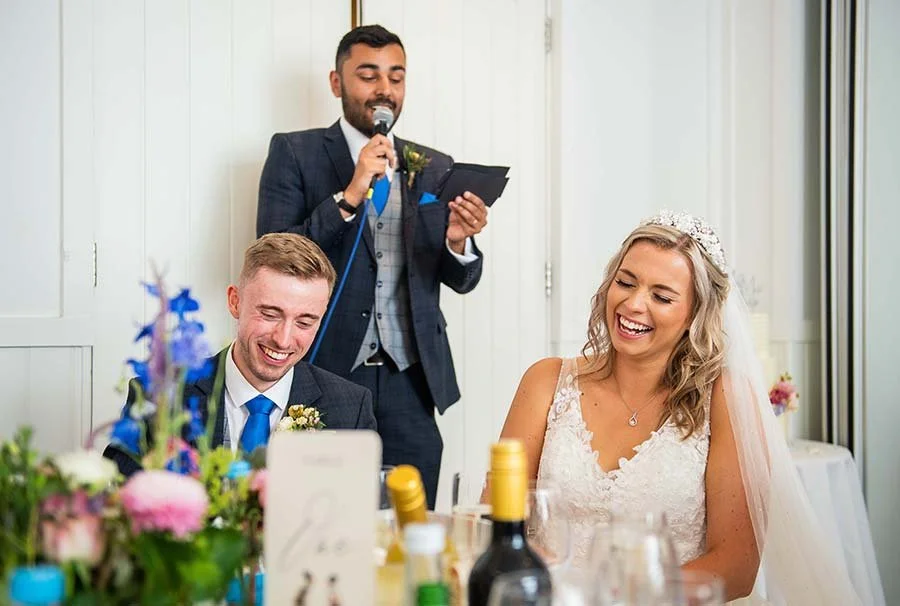Bride and groom laughing together during reception speeches at the Harbour Hotel, Brighton.