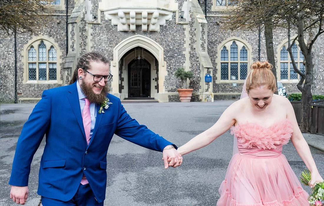 Bride and groom walking hand in hand sharing a moment at Brighton College.