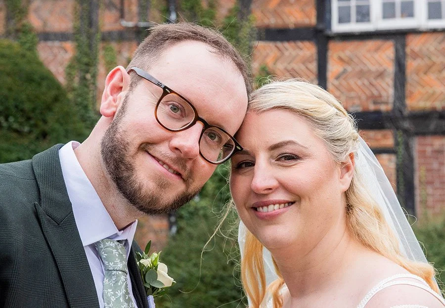 Smiling bride and groom facing the camera in a candid wedding portrait at Tottington Manor, Henfield.