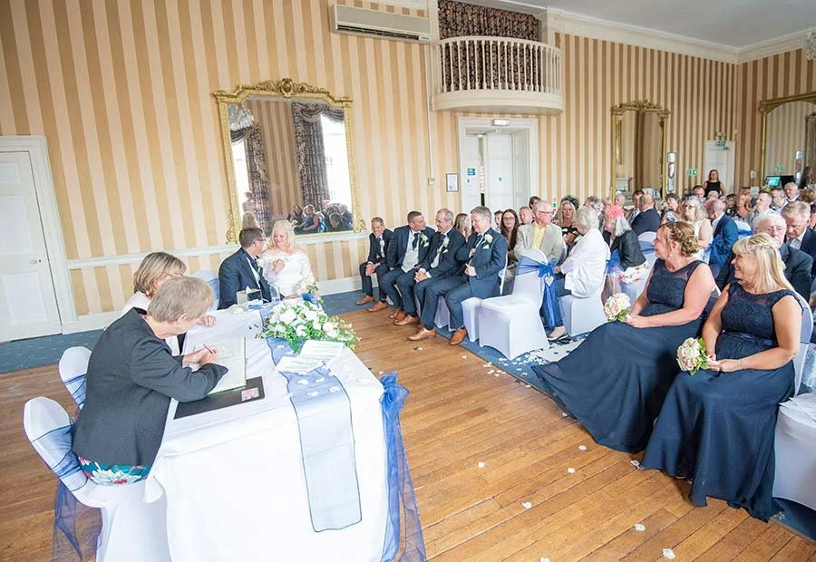 Wedding ceremony at The Norfolk Arms in Arundel, West Sussex, with guests seated and the couple exchanging vows.