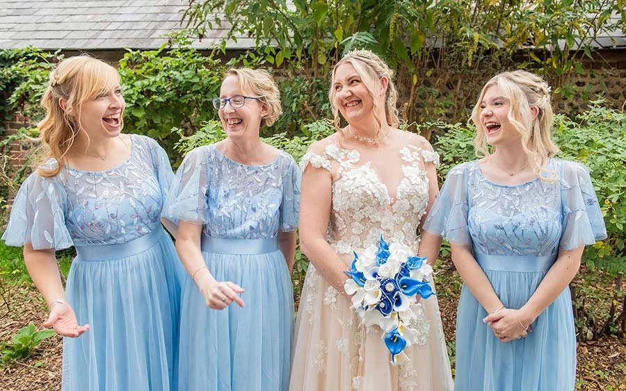 Bride and bridesmaids laughing together in a group wedding photo at Angmering Manor Hotel