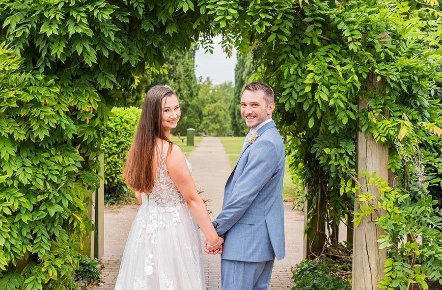 Bride and groom smiling photo for a wedding portrait outside Park House Registry Office in Horsham, West Sussex, with landscaped surroundings.