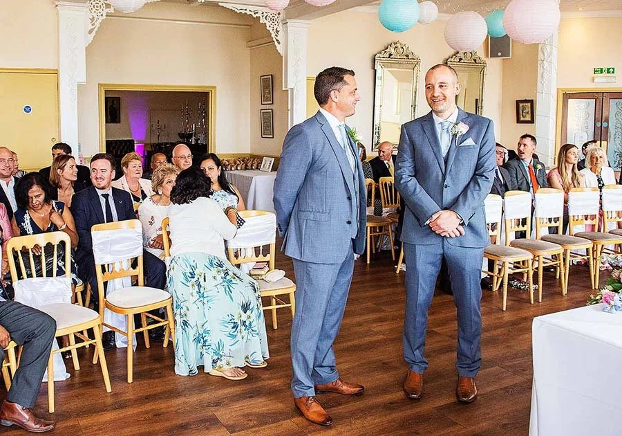 Groom smiling with his best man during ceremony at Worthing Dome, Worthing, Sussex.