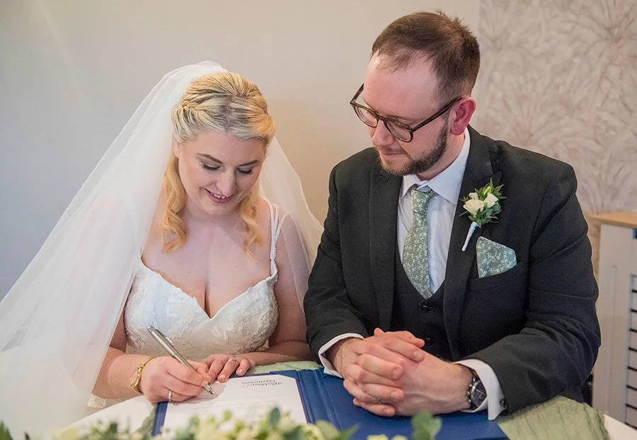 Bride and groom officially signing the wedding register, marking their marriage ceremony at Tottington Manor.