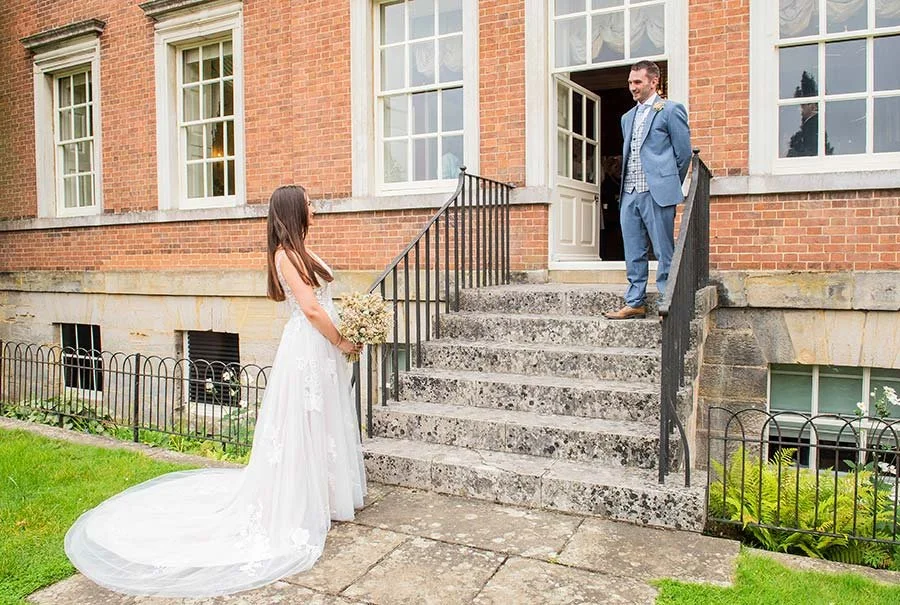 Bride and groom posing for a wedding portrait outside Park House Registry Office in Horsham, West Sussex, with landscaped surroundings.