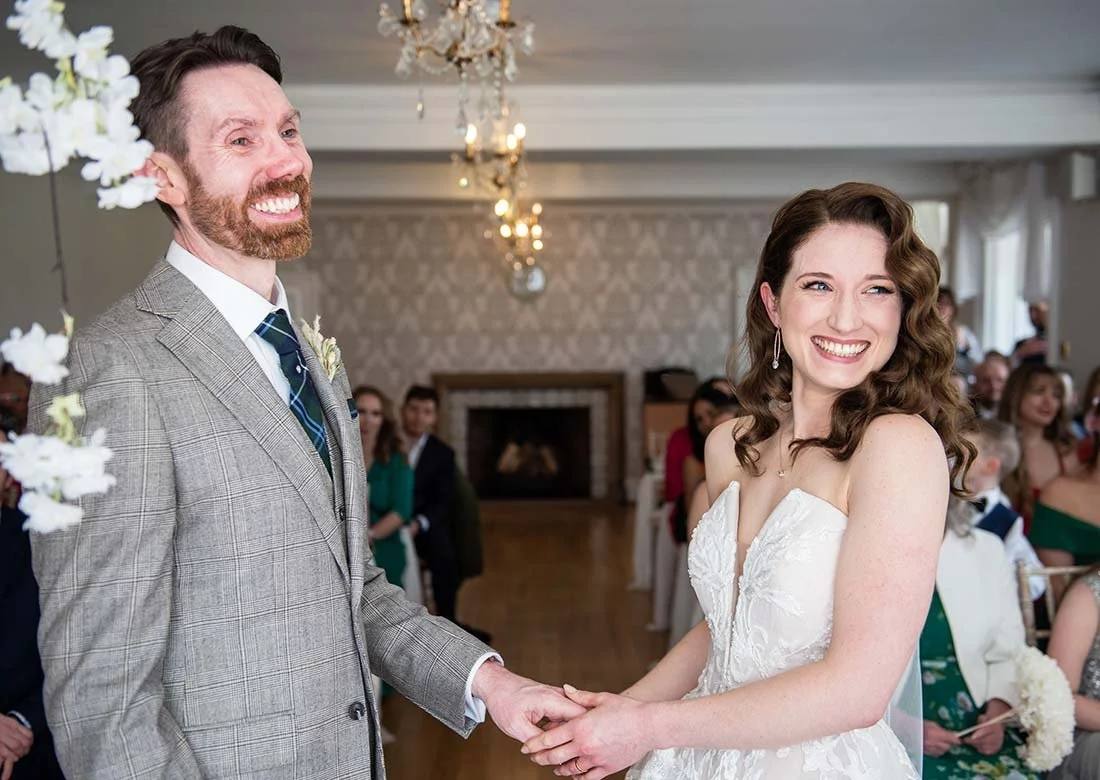 A bride and groom smiling together at their indoor wedding ceremony in the landscaped gardens of Field Place Manor House & Barns, Worthing.