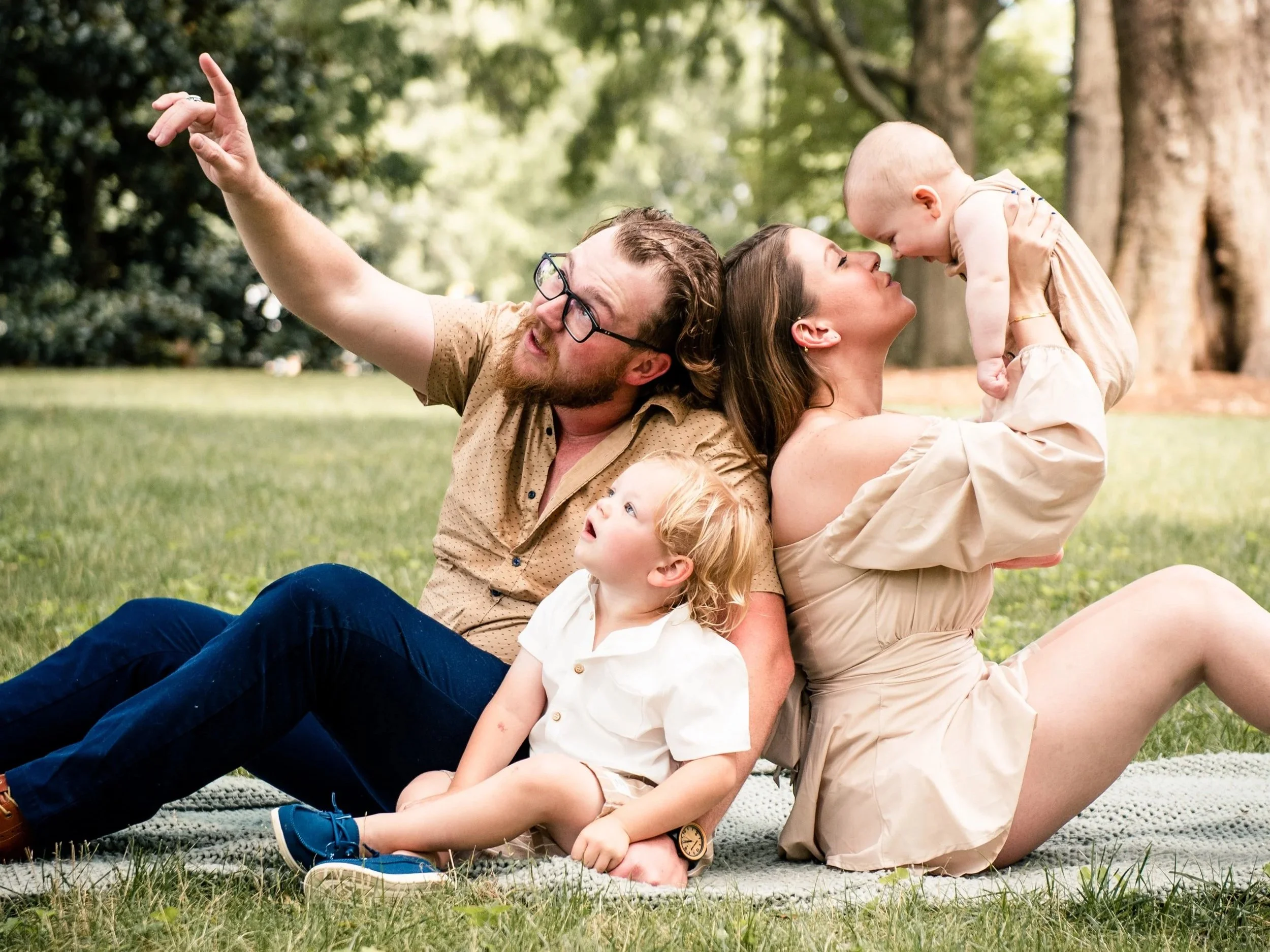 Outdoor family photography session Gibsonville NC — family of four sitting together in grass on Elon University Campus