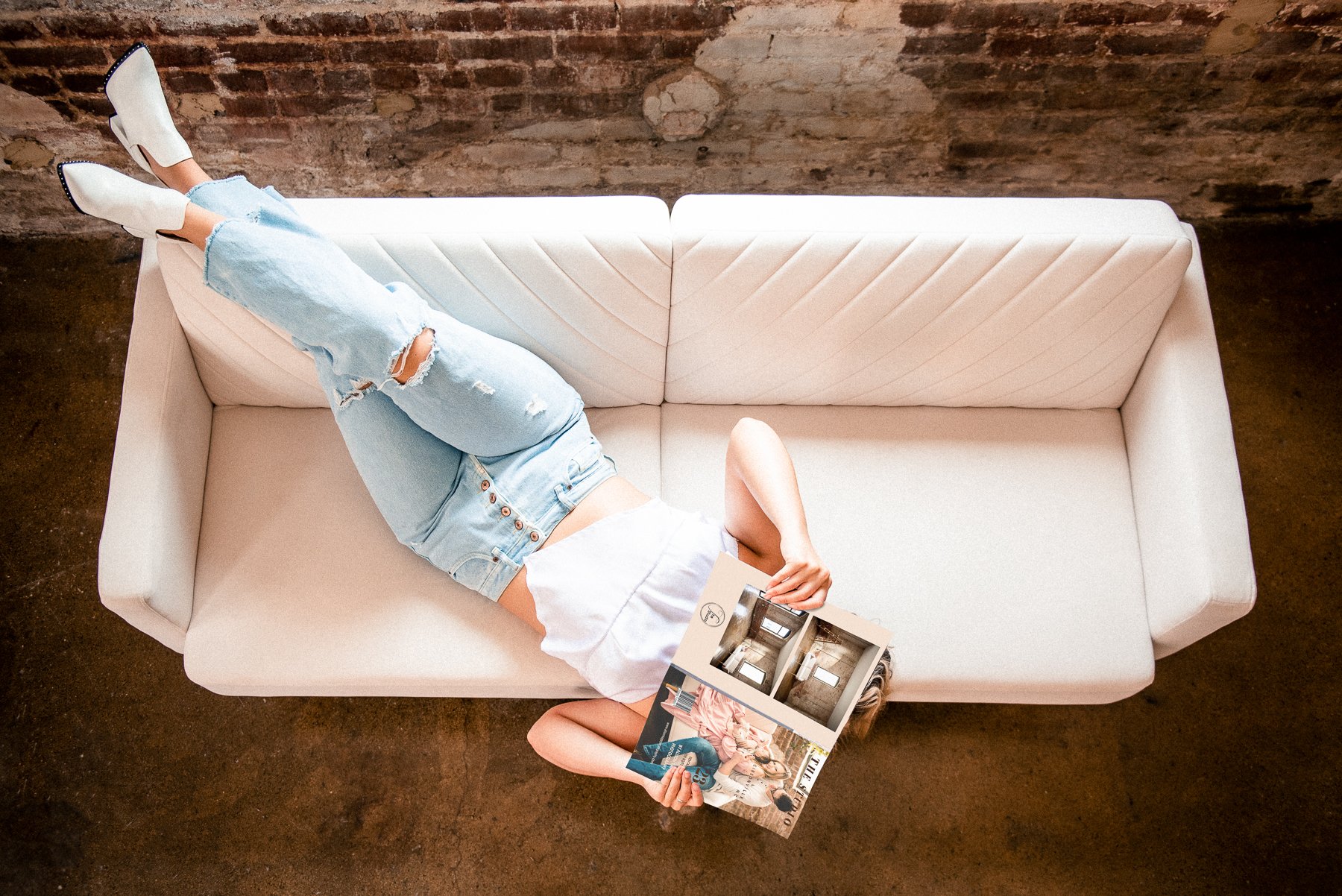 Girl laying on sofa holding a studio magazine in Alison Tapp Photography studio in downtown Gibsonville NC