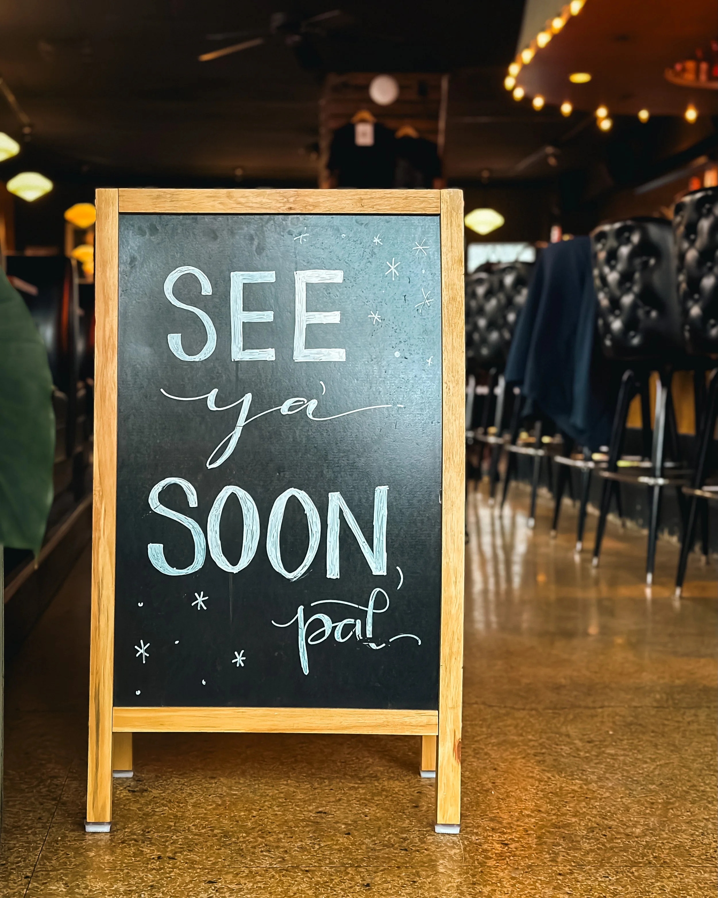 "See you soon, pal" written in white chalk on a chalkboard inside of Palomino Bar.