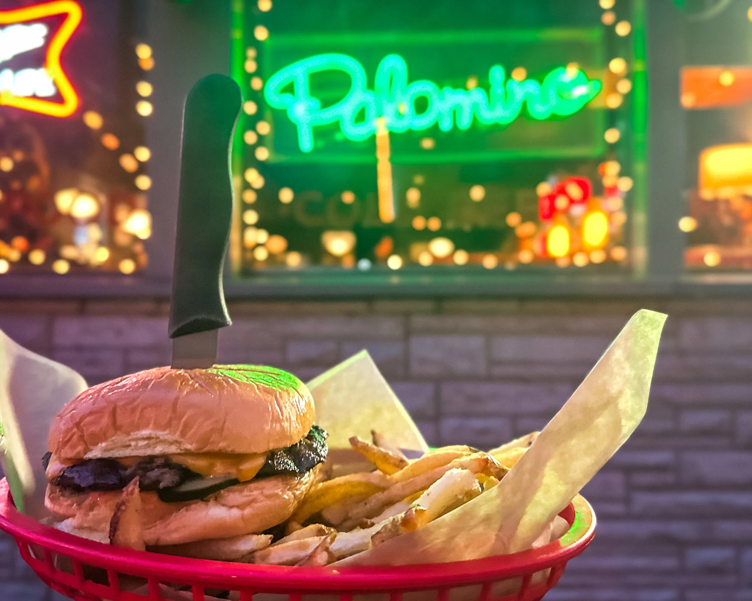 Palomino brisket burger with fries in a basket in front of the Palomino sign.