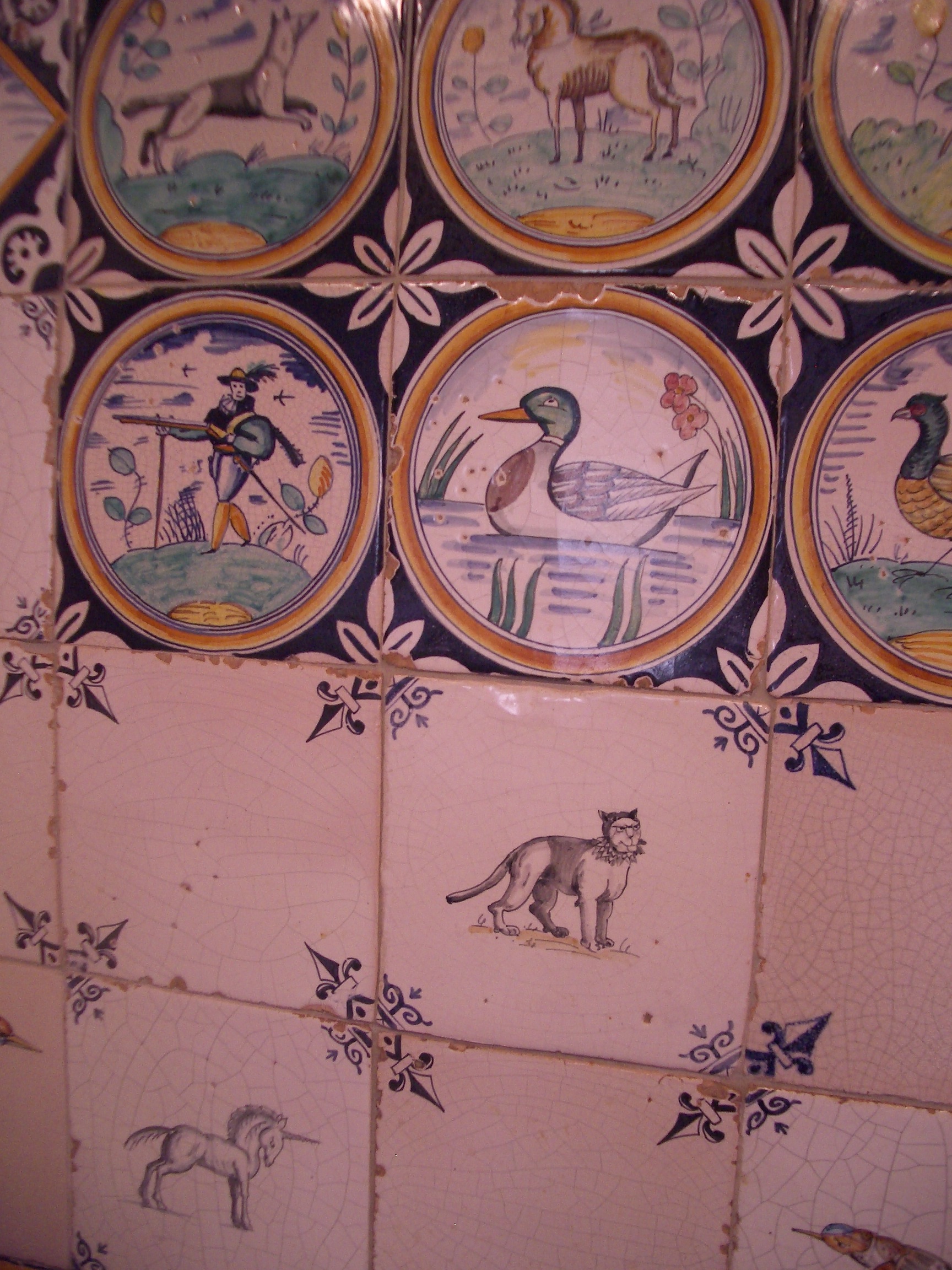 Delftware Tiles. Behind the kitchen Wolf range is a panel of reproduction early and mid-seventeenth century Dutch tiles, some depict soldiers and animals set within borders of concentric circles, others are mid-seventeenth century Dutch animal tiles with ox-head corner motifs and plain tiles with flour-de-lis corner motifs. The corner motifs are executed in the reserving technique (such that when four corners meet, they create an ornamental design). 