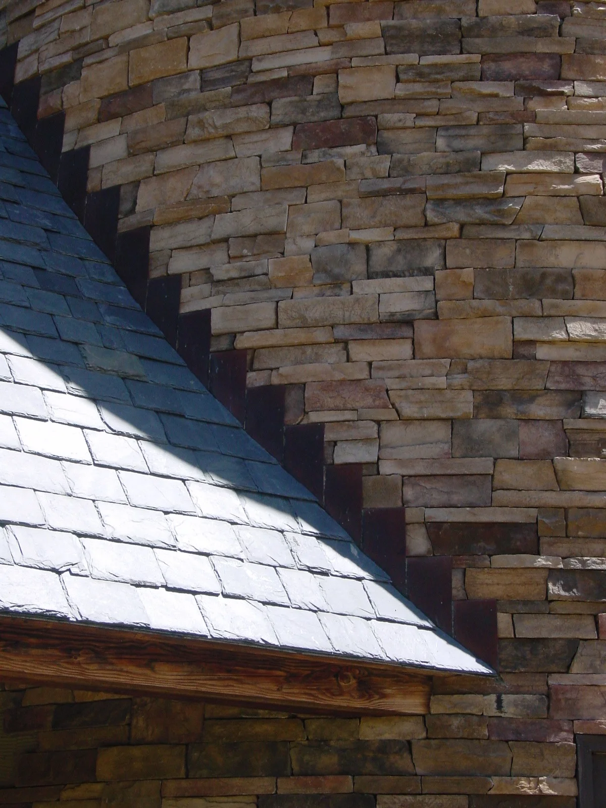 Copper step flashing at the slate roof to stone wall intersection.