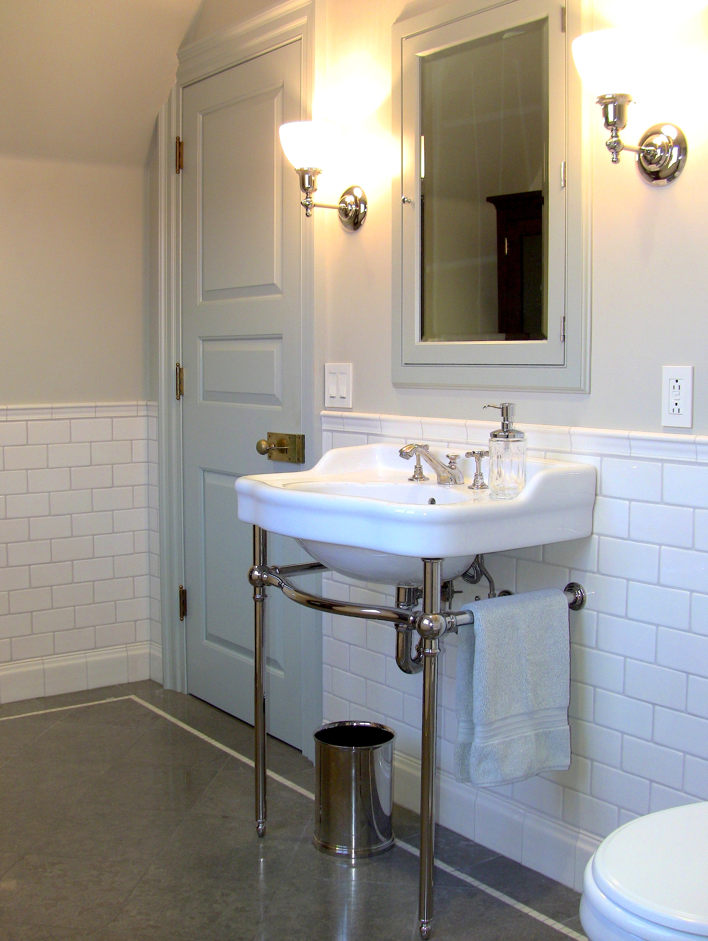 The bathroom for the Blue Bedroom above includes pedestal sink, handmade crackle-glazed tile wainscoting and honed Lagos Azul limestone flooring with a polished marble accent stripe .