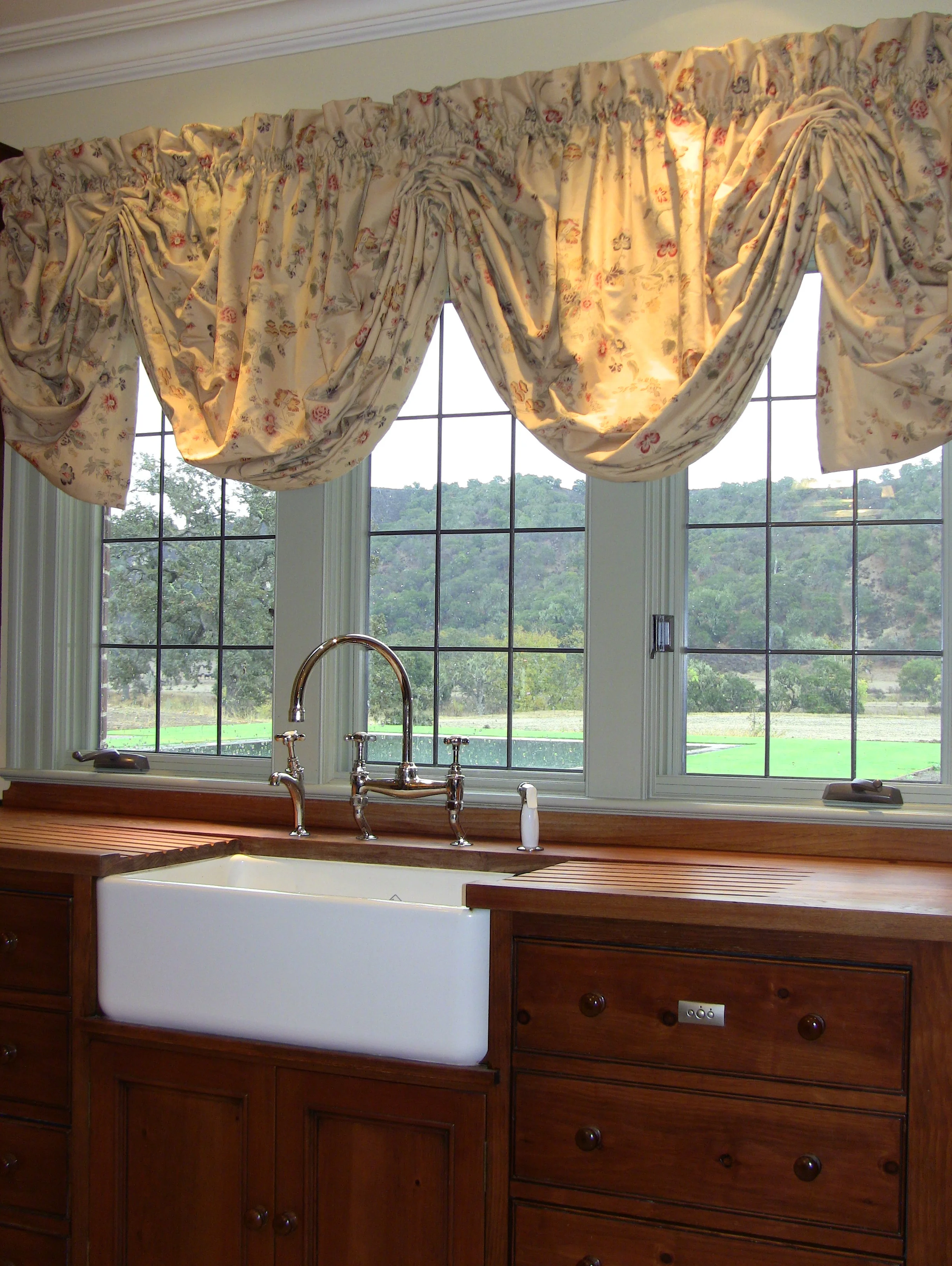 A Shaws of Darwen heavy duty ceramic fireclay sink is set in a custom teak worksurface with integrated drain boards and flanked on either side by double Fisher Paykel DishDrawers