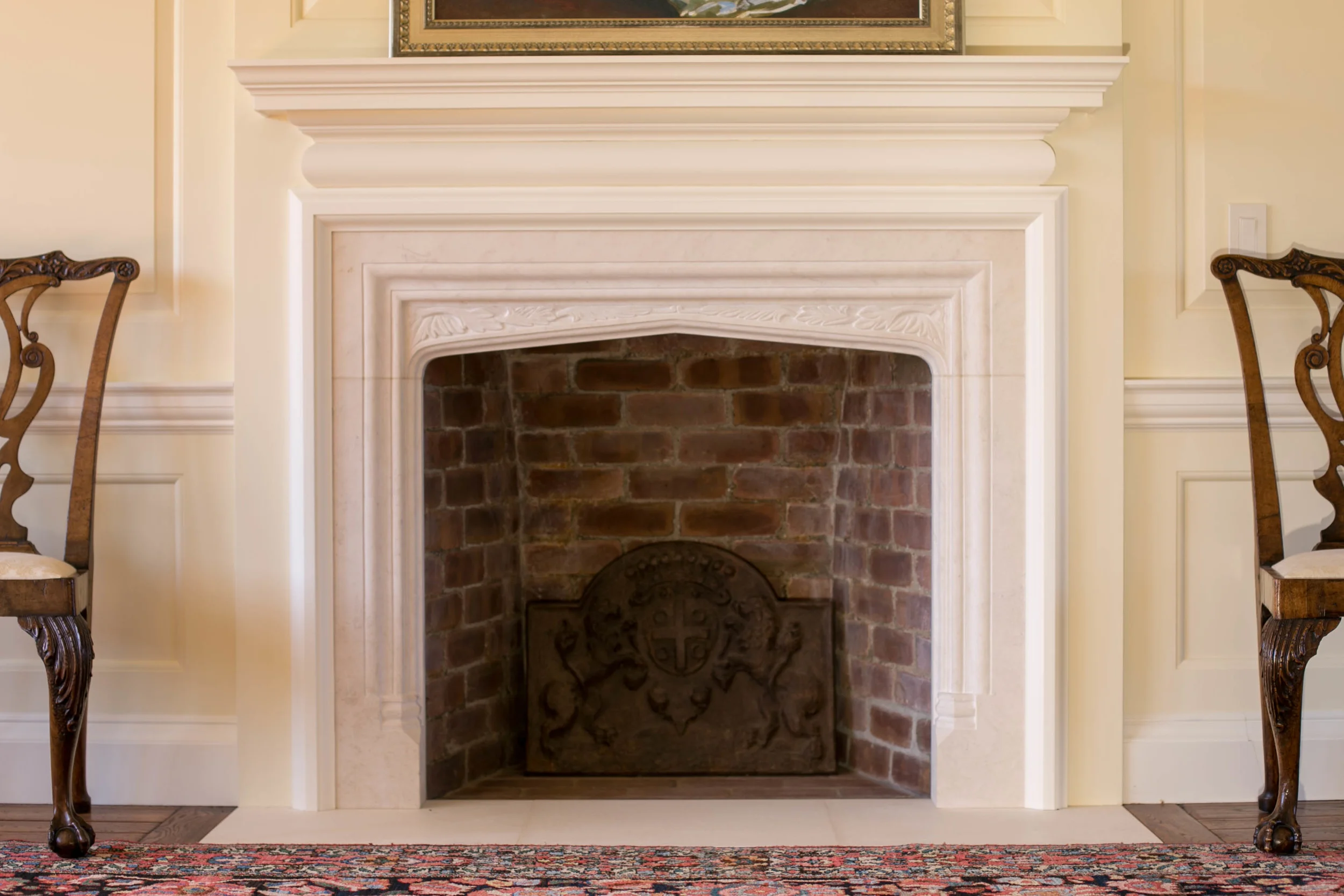 A stone mantel in the Tudor style with foliate carving to the spandrels in English Bathstone