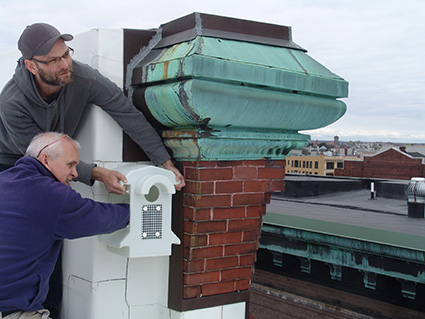 Peter Green, standing, and Peter Gagne install a nest for a kestrel in hopes the tiny raptor will scare away the pigeons nesting on the building across the way. (Frank Carini/ecoRI News)