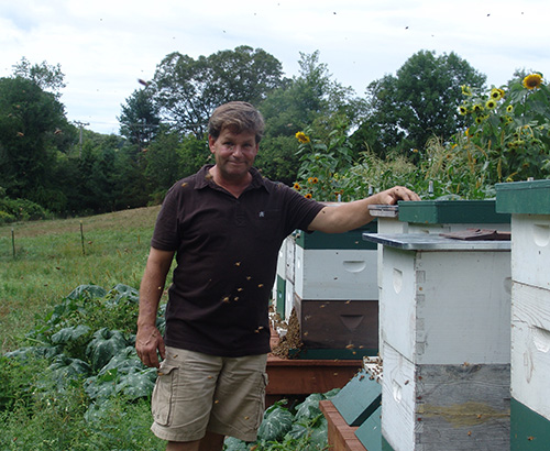 Jon Nelson surrounded by his hives and bees at his friend’s farm in North Smithfield, R.I. (Frank Carini/ecoRI News)