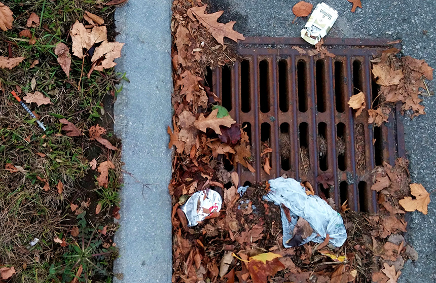 A cigarette box, beer can and a hypodermic needle are just three of the littered items threatening to clog and pollute this storm drain on an entrance ramp to I-195 near India Point Park in Providence. Each is a commonly littered item, according to representatives of southern New England’s departments of transportation. (Kevin Proft/ecoRI News photos)