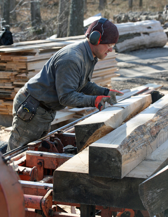 Rob Swanson moves trimmed logs onto the carriage of the sawmill in preparation for the final cuts into boards.