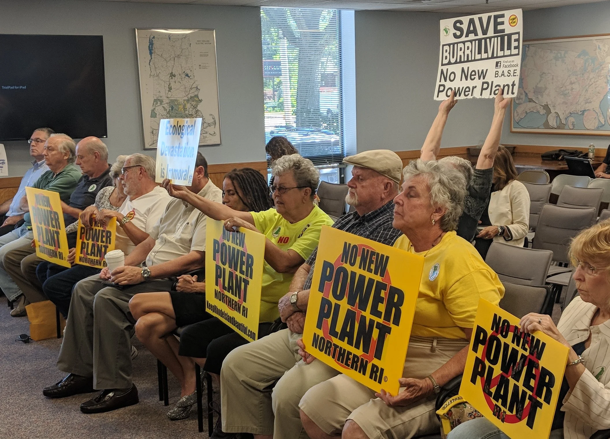 Project opponents held signs during the recent Rhode Island Energy Facilities Siting Board meeting.