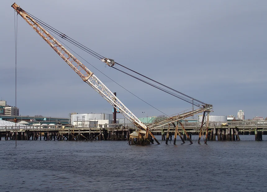 This floating crane owned by an East Providence man sank in the Providence River a year ago. The barge was leaking oil and the owner was cited for violating five pollution laws. But nothing has been done. (Frank Carini/ecoRI News)