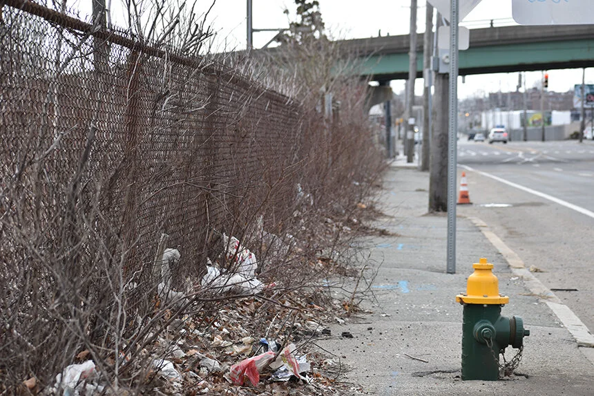 Besides hosting an array of polluting businesses that store toxic materials, the city, state, and most businesses do little to address the neglect along Allens Avenue, such as trash that collects along rusting and bowing chain-links fences, the overgrowth of weeds that obstruct sidewalk passage, and the grit and debris that covers the shoulder where bicyclists ride.