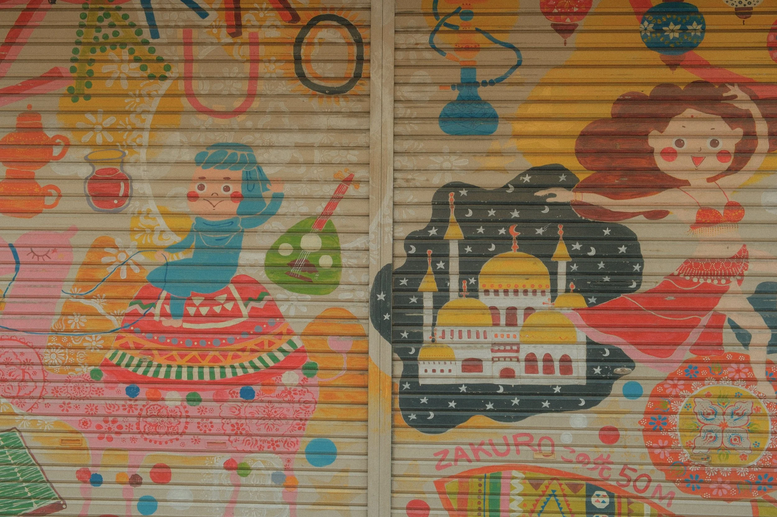 Colorful mural on a wall depicting children with Middle Eastern motifs, including a girl with a blue hijab and a girl wearing a red dress with a desert castle, surrounded by objects like teapots, a musical instrument, and decorative patterns.