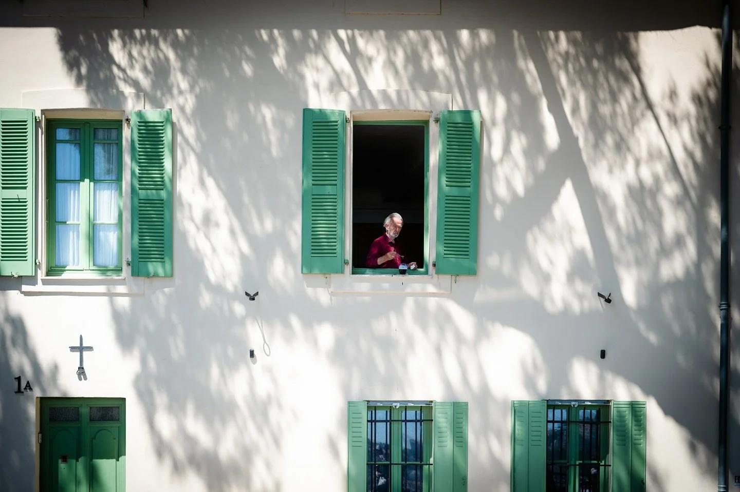 Cannes, France.
A priest (I assume) sits at his window, lunch in hand,
bathed in dappled midday light.
A quiet pause from the glamour city&rsquo;s buzz.
