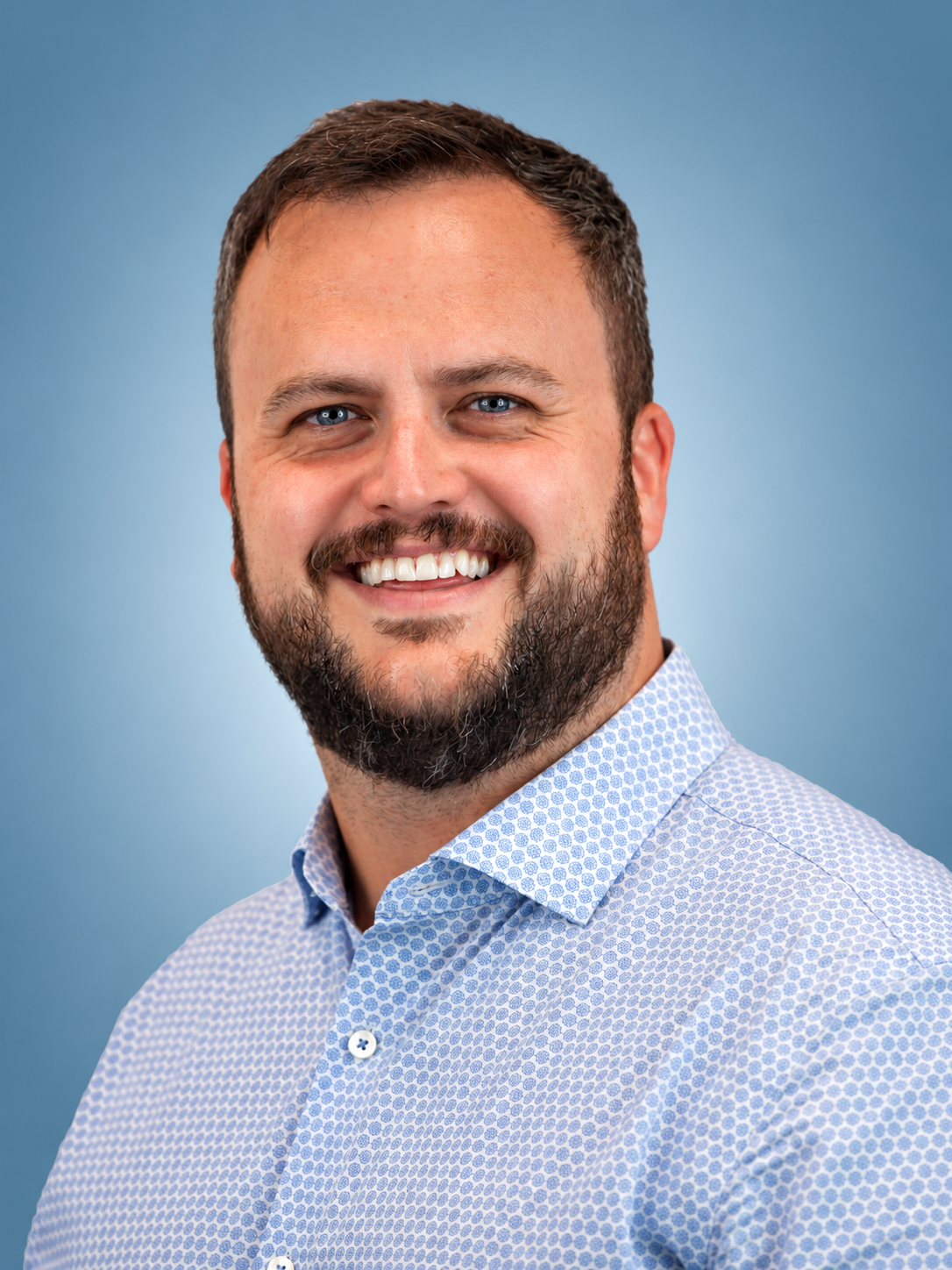 Smiling Bearded Man in Blue Shirt.png