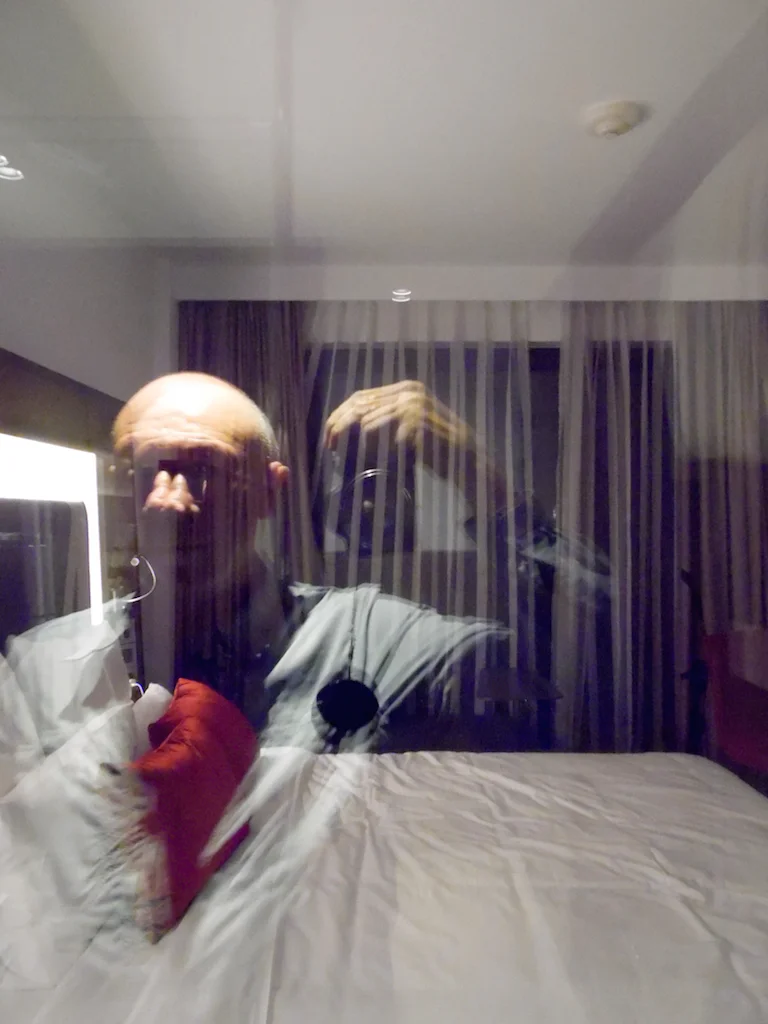 I took this photo of my reflection from the windowed divider in my hotel room. The reflected red pillows appears like a heart exposed!