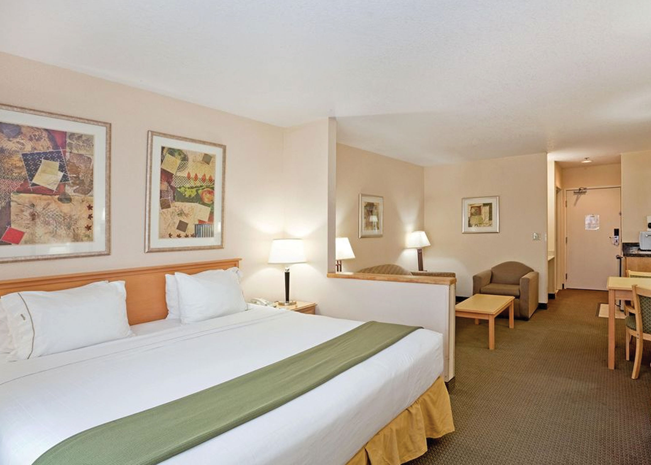 hotel room with bed, soft seating area and case goods