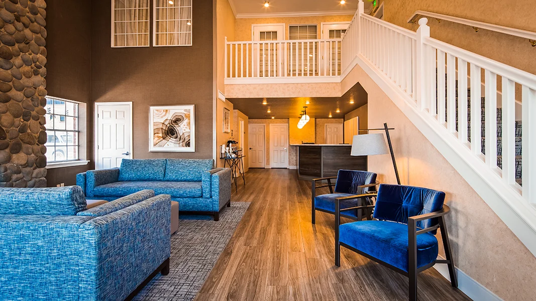 hotel lobby, white stair case, blue soft seating, dark brown reception desk, brown wall paint