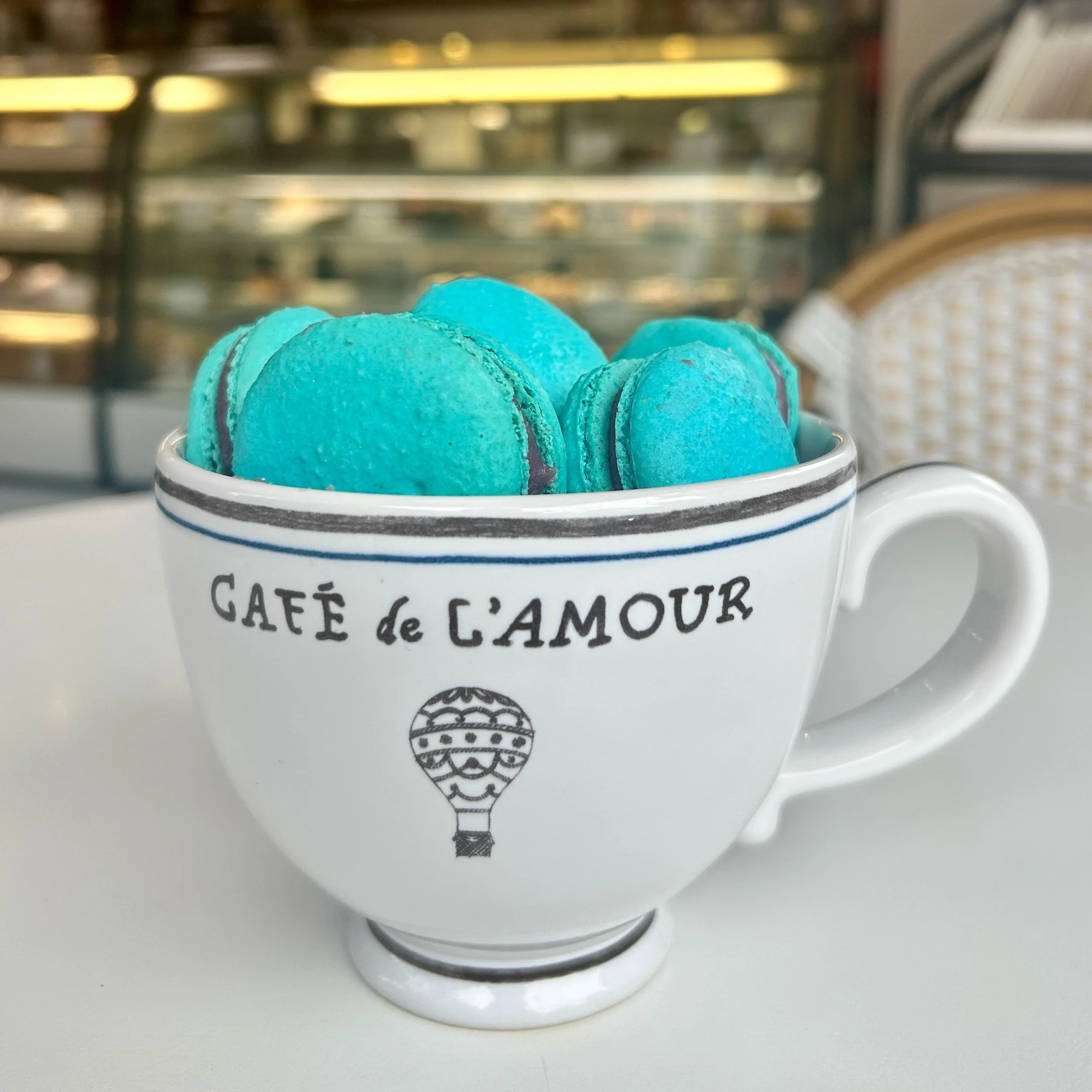 Turquoise macarons piled in a white coffee cup