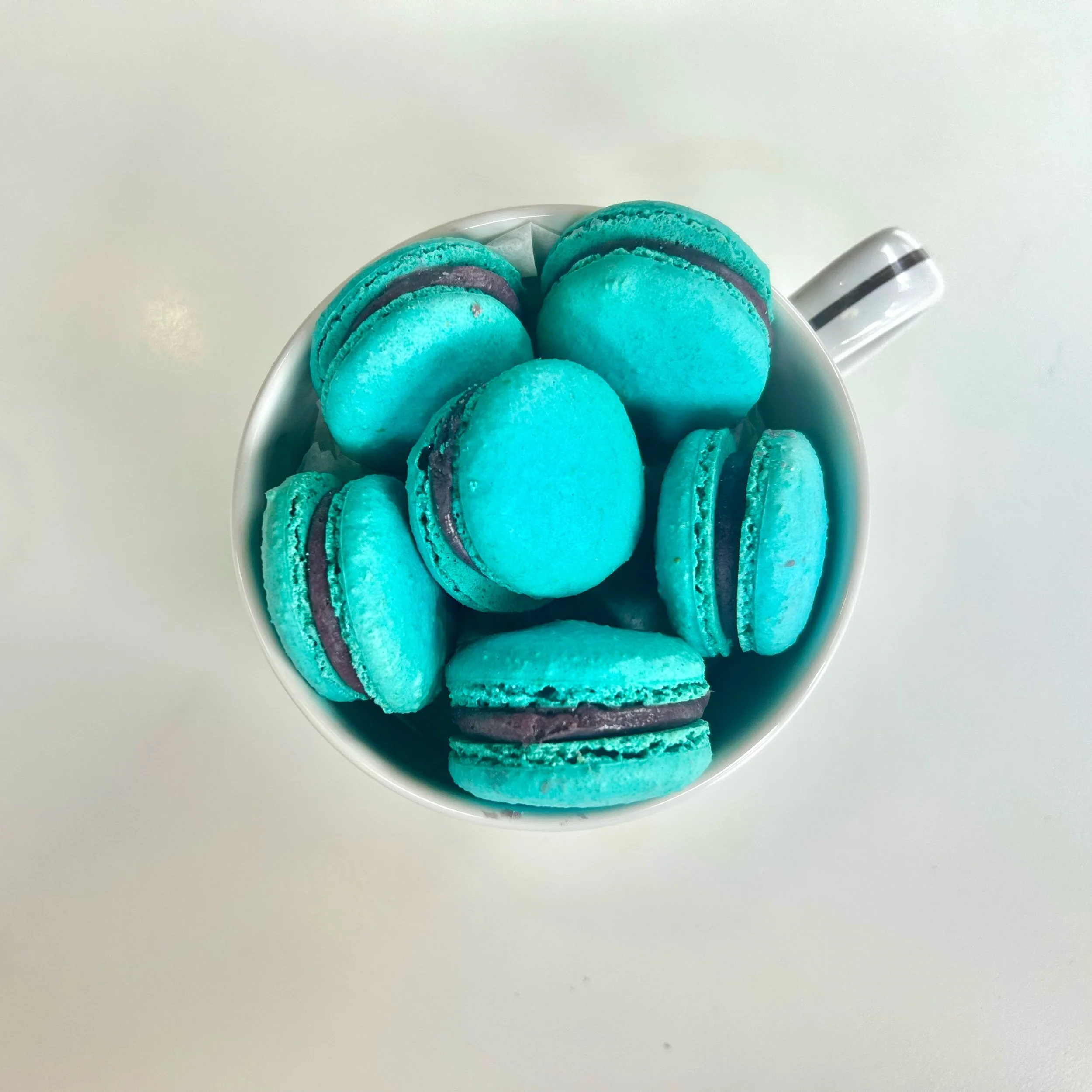 Top view of turquoise macarons in a white cup