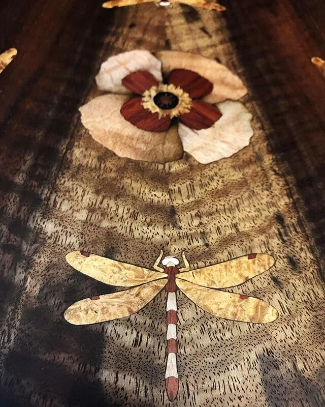 This has been an inlay-heavy month, with some beautiful projects to work on. 
Our customer wanted non-shiny dragonflies and a poppy on the back of this beautiful book matched walnut resonator, so we used woods and mammoth ivory. Such a fun project, s