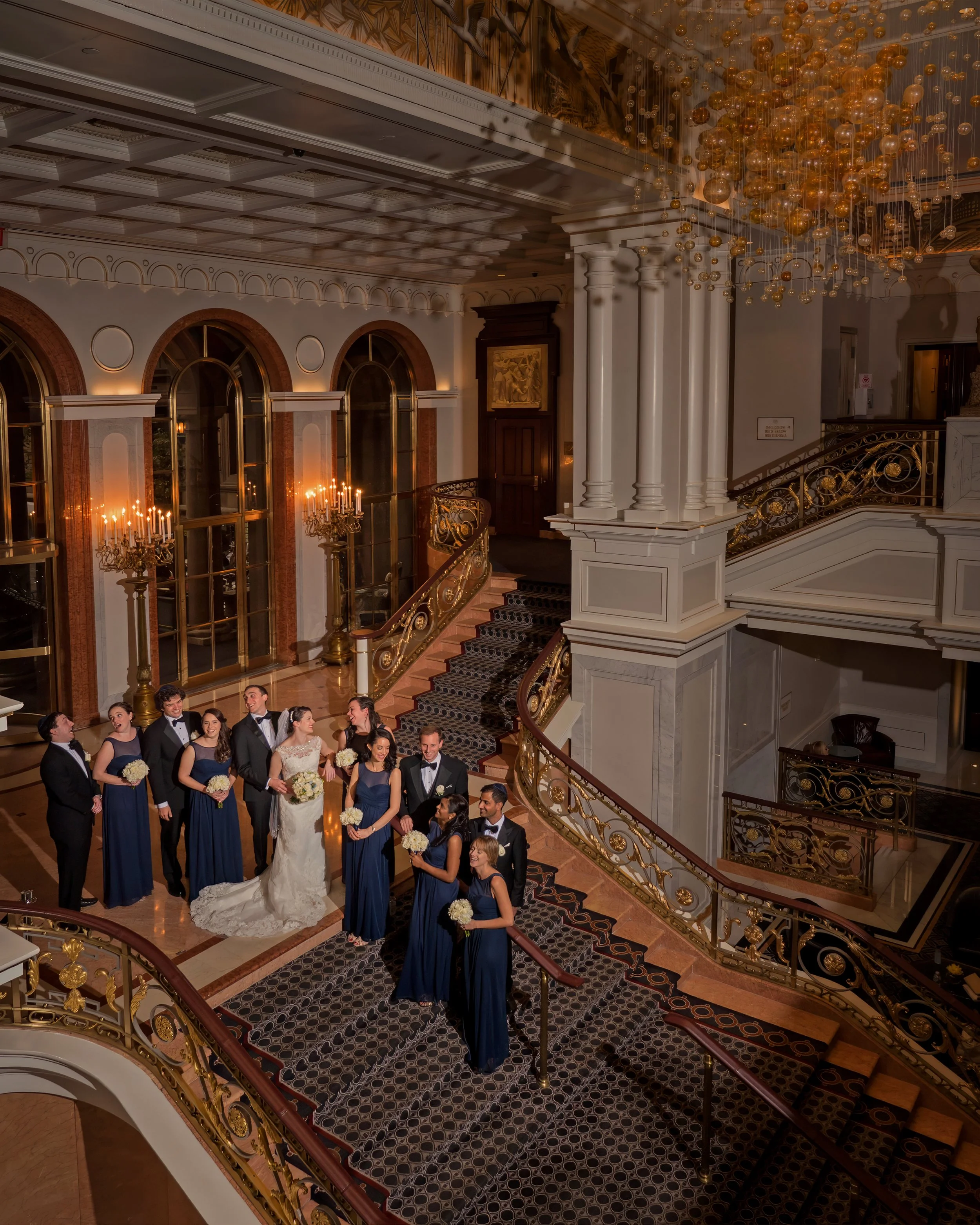 Wedding party gathered atop the grand foyer staircase at the Lotte New York Palace Hotel.