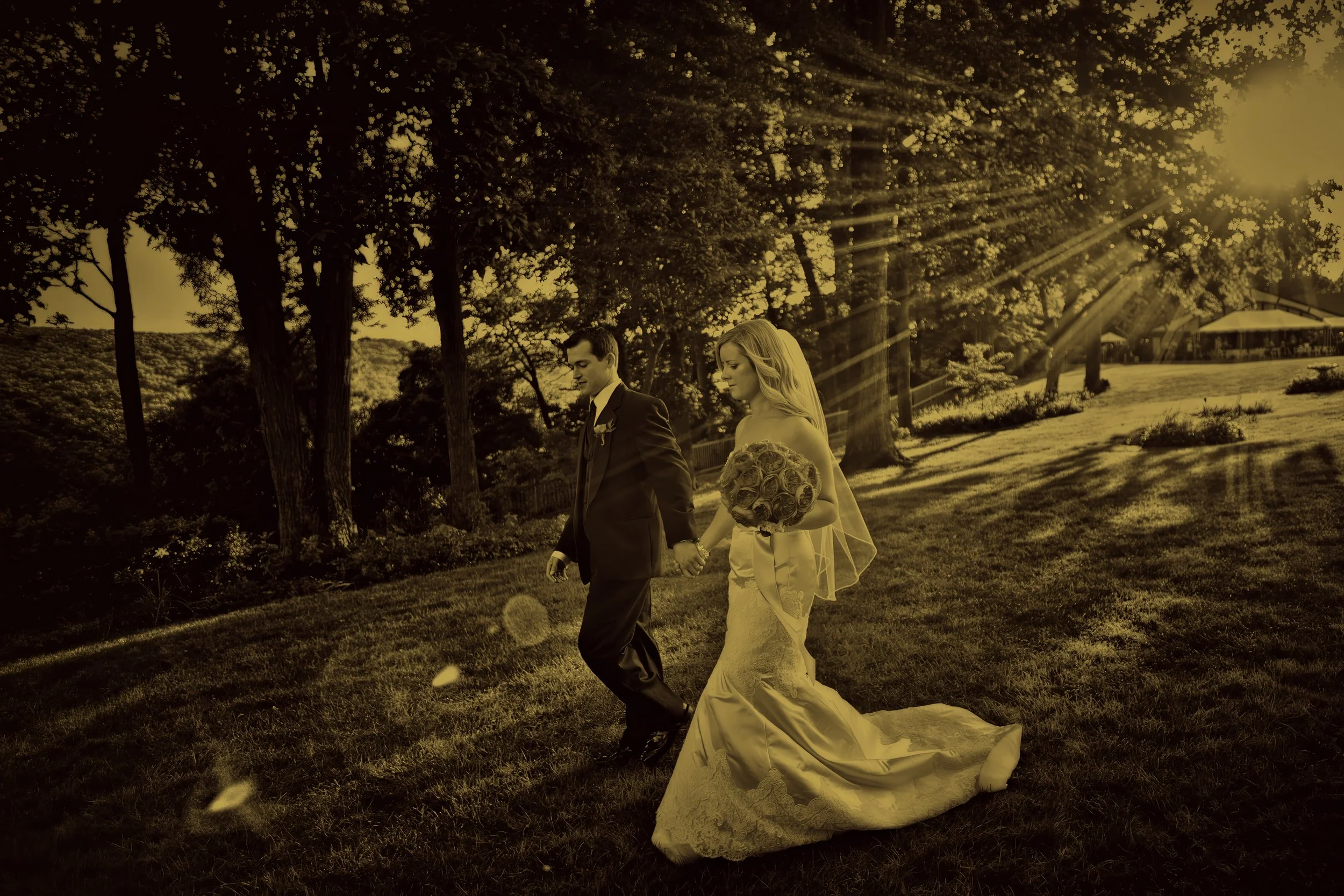 Bride and groom holding hands walking into sun flare during a fine art Connecticut wedding