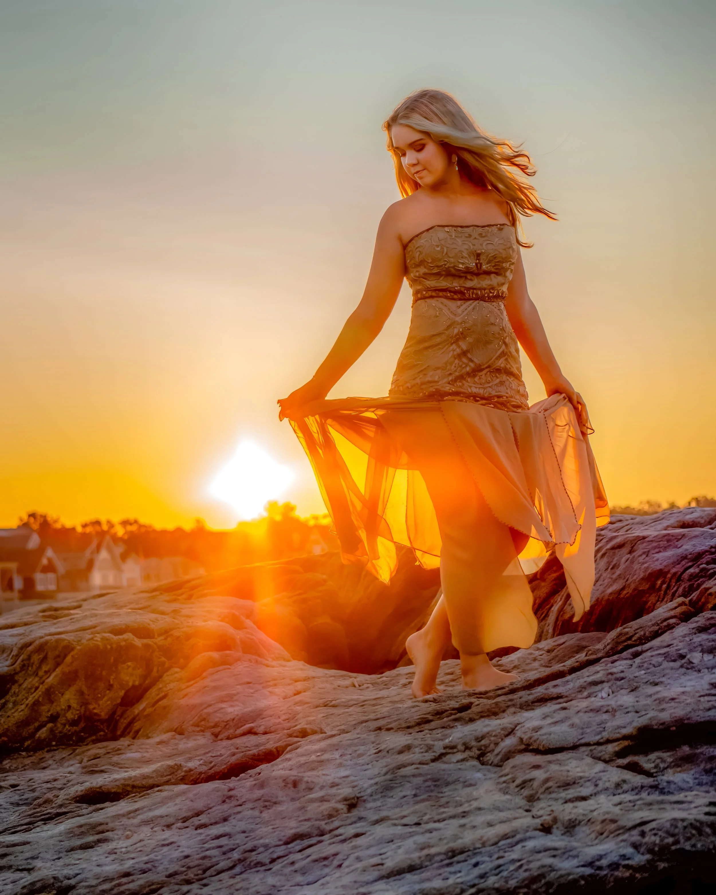 Senior portrait of a young adult on the Connecticut shoreline at sunrise, with warm, glowing light and calm reflection