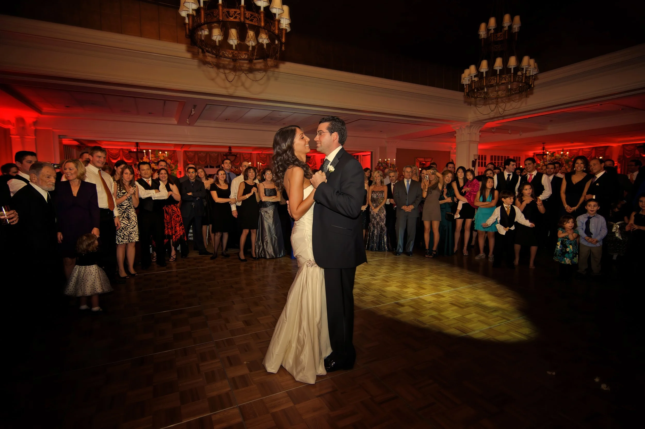Bride and groom share their first dance surrounded by guests.