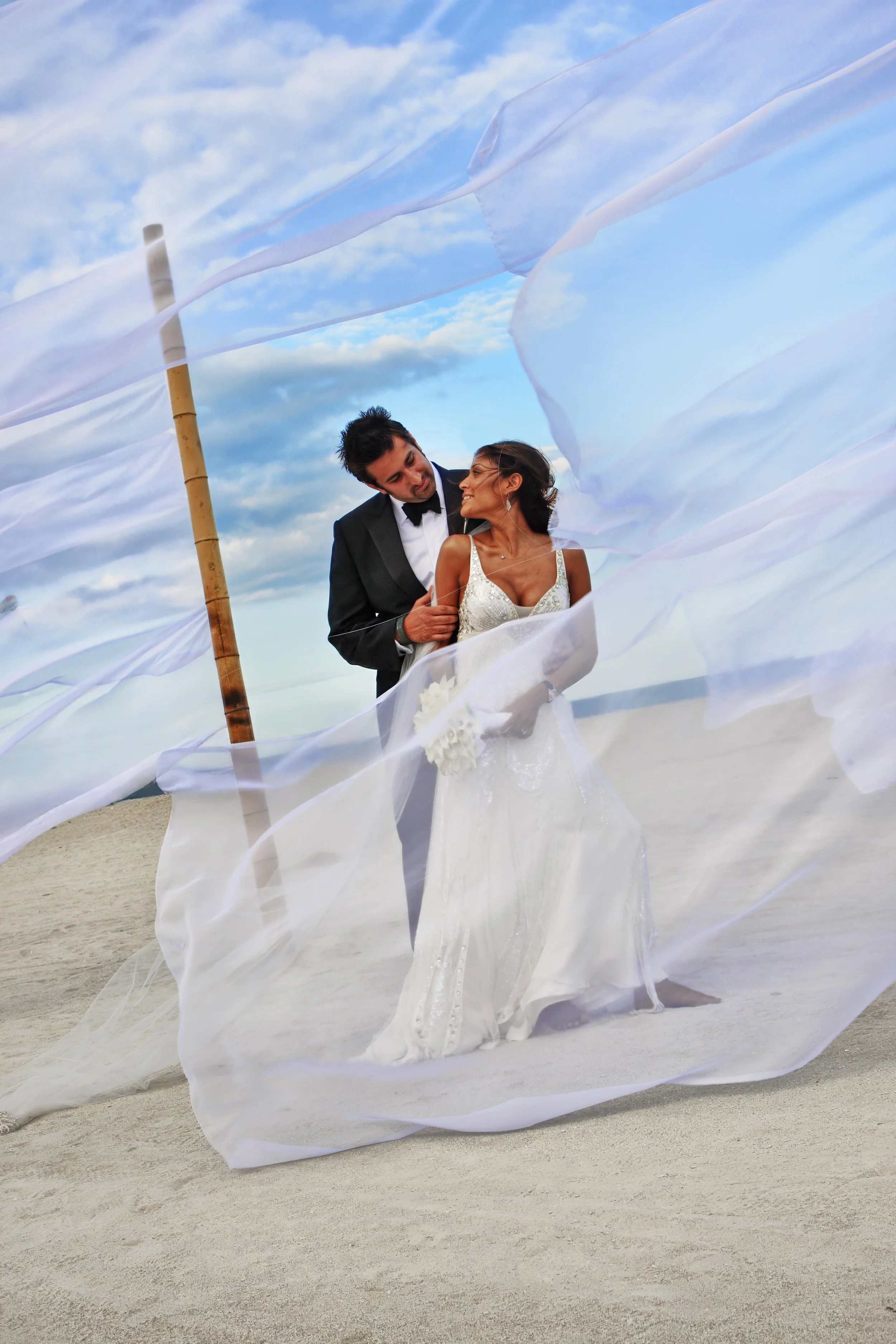 Romantic bride and groom embracing on a beach, captured with editorial discretion and refined composition