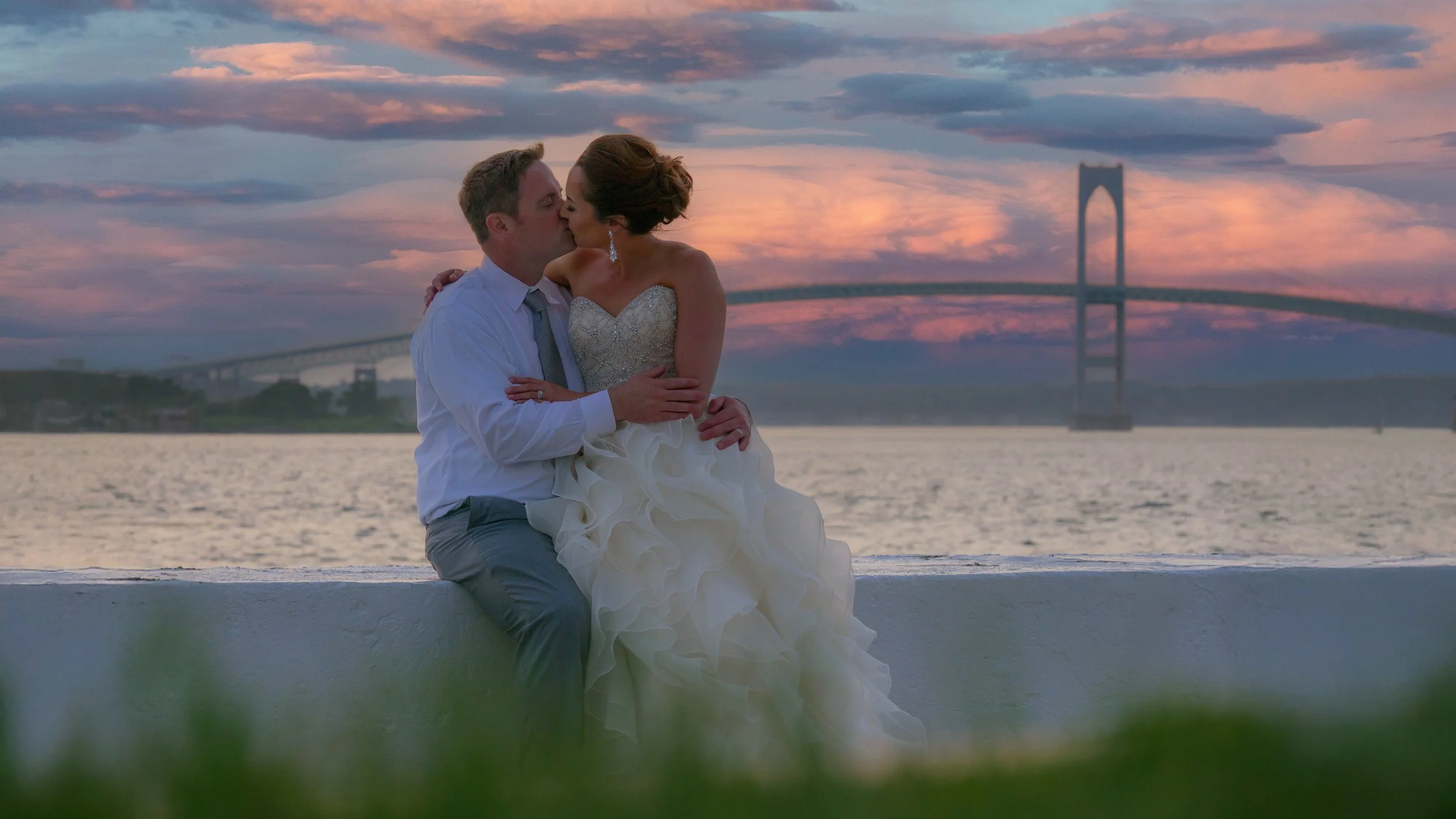 Bride and groom kiss on the sea wall at Belle Mer, Newport, Rhode Island