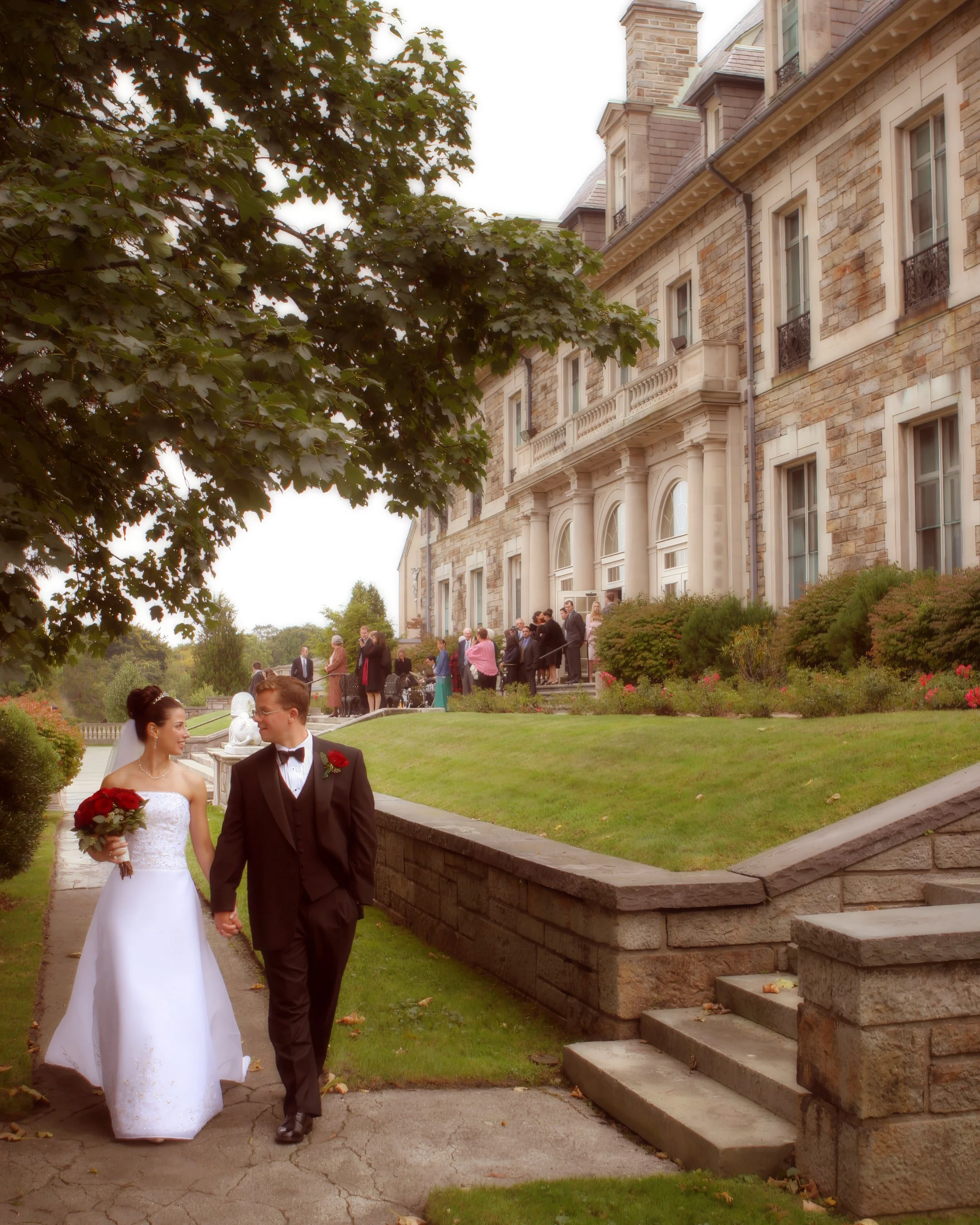 Bride and groom walking hand in hand across the grounds of Aldrich Mansion with the mansion in the distance.